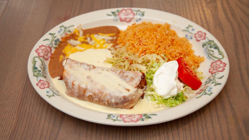 Chimichanga Con Queso · Choice of chicken, ground beef, pork, or shredded beef in a large flour tortilla. Drizzled with chile con queso sauce on top and sour cream on the side.