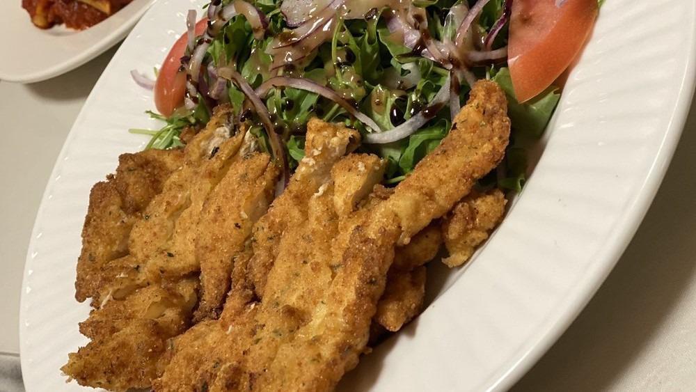 Chicken Milanese · breaded breast of chicken pan fried topped with baby greens, red onions tomato salad and shavings of parmigiano.