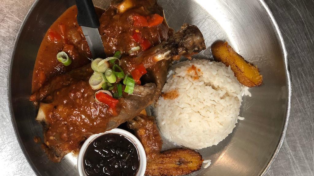 Chilindron De Cordero · Tender meaty lamb shank slowly braised in a rich merlot wine sauce and vegetable mirepoix. Served with white rice, black beans and sweet plantains.