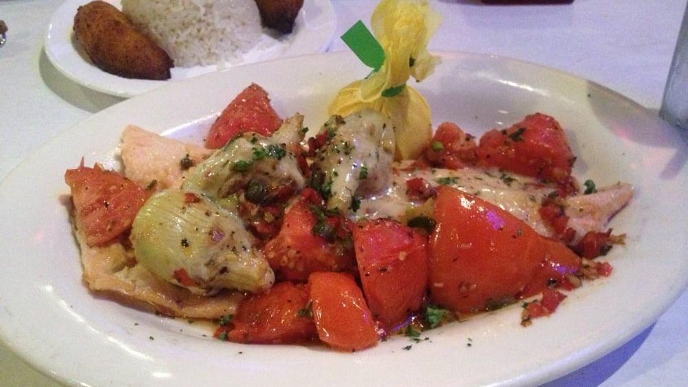 Trucha Al Modo Mio · Pan-seared rainbow trout, sautéed artichoke hearts, tomatoes, red peppers and capers laced with muga white wine sauce. Served with white rice and sweet plantains.