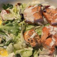 Salmon Salad · Grilled Salmon sits atop a bed of Lettuce medley with cucumbers, tomatoes, red onions and eg...