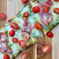 Pesto Prosciutto Flatbread Pizza · Basil pesto, thinly sliced prosciutto, italian cheese blend and cherry tomato. Served warm o...