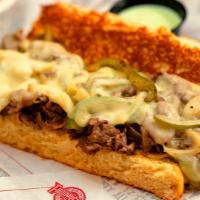 Philly Cheesesteak W Fries · Made the Philadelphia way! Fresh shaved Ribeye Steak topped with Grilled Peppers, Onions, an...