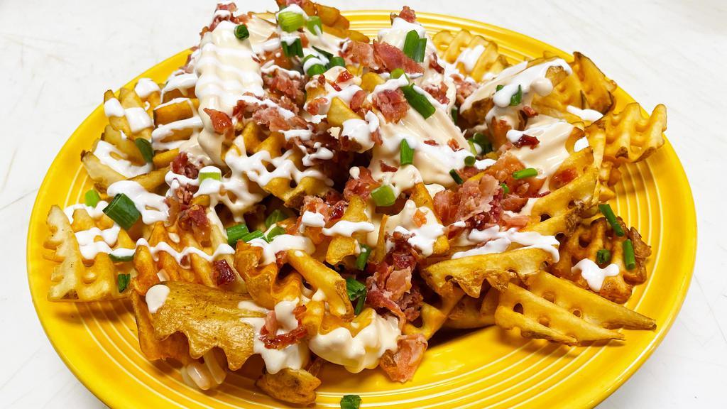Beer Cheese Fries · A generous portion of waffle fries smothered in our house made beer cheese sauce.  Topped with chopped bacon, sour cream and green onions.