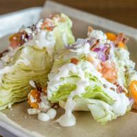 Wedge Salad · Iceberg lettuce, blue cheese dressing, blue cheese, bacon, tomatoes, red onions.