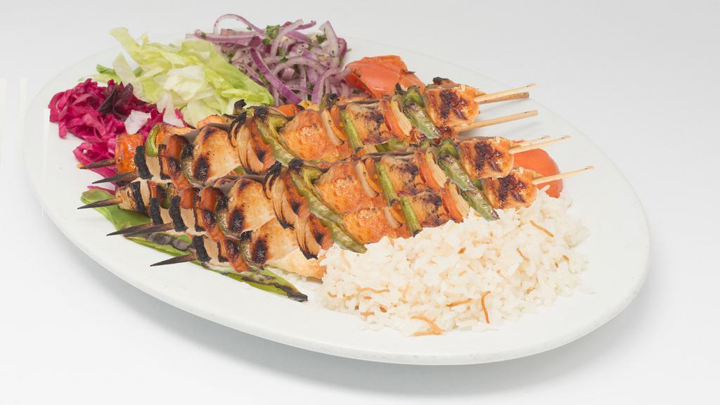 Baby Chicken Shish · Small pieces of chicken grilled with tomato, pepper and onion on a skewer. Served with a side of rice, red cabbage, and chopped onion.