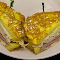 Monte Cristo · Egg-dipped bread grilled with swiss, turkey, and ham, topped with powdered sugar. Served wit...