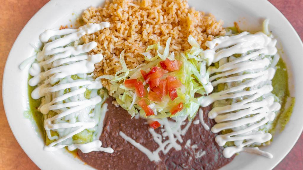 Enchiladas Suizas · Corn tortillas filled with shredded chicken, topped with green sauce, sour cream, and served with rice beans.chips and salsa