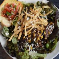 Santa Fe Salad · A bed of fresh salad greens layered with steak, fire roasted vegetables, tortilla strips, to...