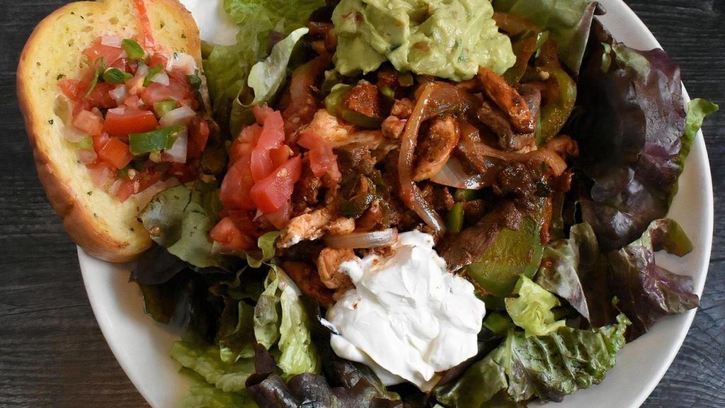 Fajita Salad · Crisp garden greens with fajita-style steak and chicken, bell peppers and onions. Topped off with sour cream and guacamole.