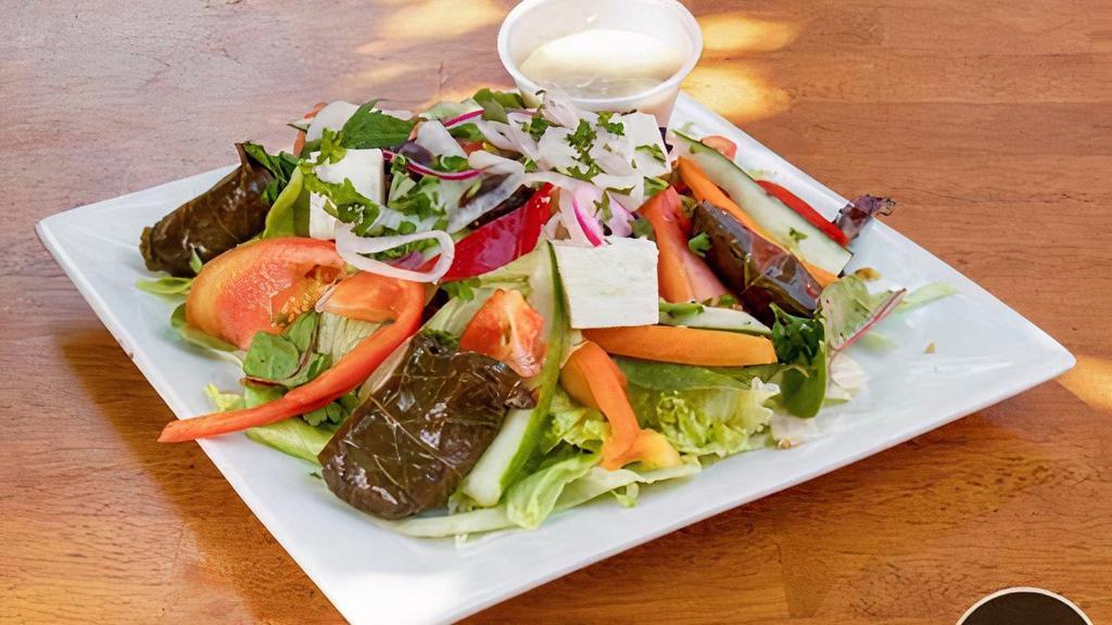 Greek Salad · Crisp lettuce, cucumbers, tomatoes, onions, green peppers, feta cheese, kalamata olives, Dolmadakia, anchovies, and house dressing.