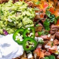 Carne Asada Fries · Grilled tender steak strips on a bed of fries. Topped with cheese sauce, sour cream, guacamo...