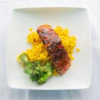 Sweet Heat Glazed Salmon · Salmon filet over yellow rice and broccoli drizzled with sauce.