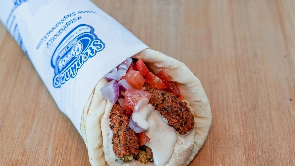 Falafel Wrap · Falafel pieces wrapped in pita bread with tomatoes, onions, hummus, and tahini sauce.
