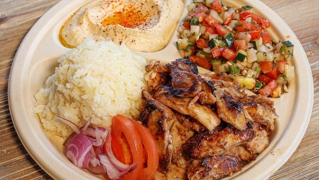 Chicken Shawerma Plate · Chicken leg and thigh sliced from a vertical spit. Served with tahini and garlic sauce, hummus, Israeli salad, rice, and two pieces of pita bread.