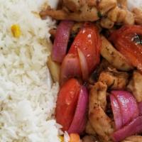Pollo Saltado · A chunk of chicken, red sauteed onions, tomatoes, soy sauce, and spring onions served on a b...