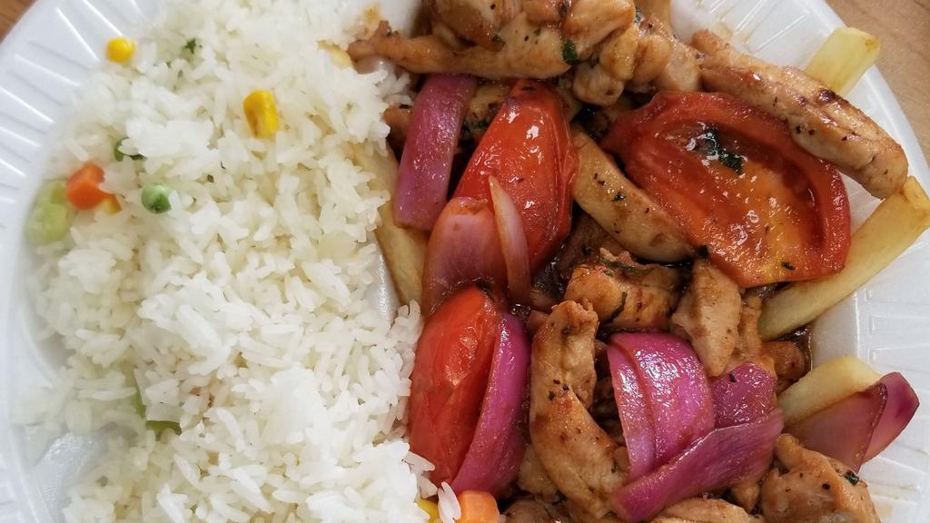 Pollo Saltado · A chunk of chicken, red sauteed onions, tomatoes, soy sauce, and spring onions served on a bed of fries with rice.