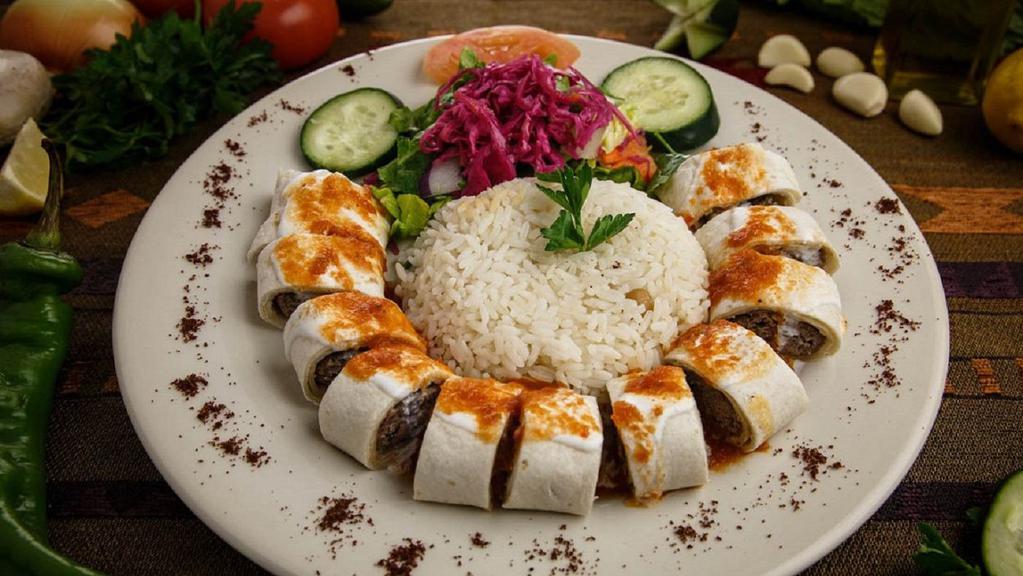 Sultan Kebab · Freshly ground lamb on a skewer char-grilled and wrapped in flat bread, cut into sections, topped with garlic yogurt and tomato sauce. Served with rice and house salad.