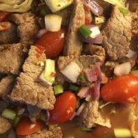 Spicy Beef Salad* · Sliced grilled beef mixed with cucumbers, tomatoes, onions, and Thai spicy herbs in Thai vin...