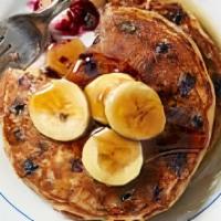 Blueberry Banana Pancakes · blueberry pancakes topped with bananas and warm syrup