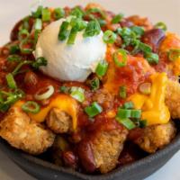 Fiesta Tot Appetizer · A skillet loaded with golden brown crispy tater tots, covered with NC’s hearty chili con car...