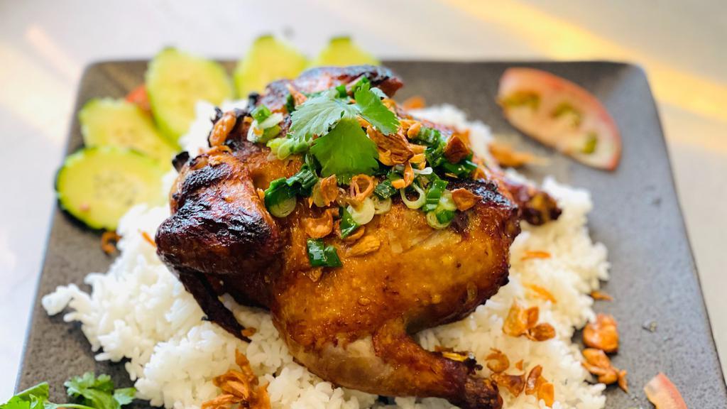 Airport Chicken (House Special) · Cornish hen fried with crispy skin and tender meat on the inside served on a bed of rice with crispy shallots and green onion on top along with slices of cucumber and tomato, side dipping fish sauce.
