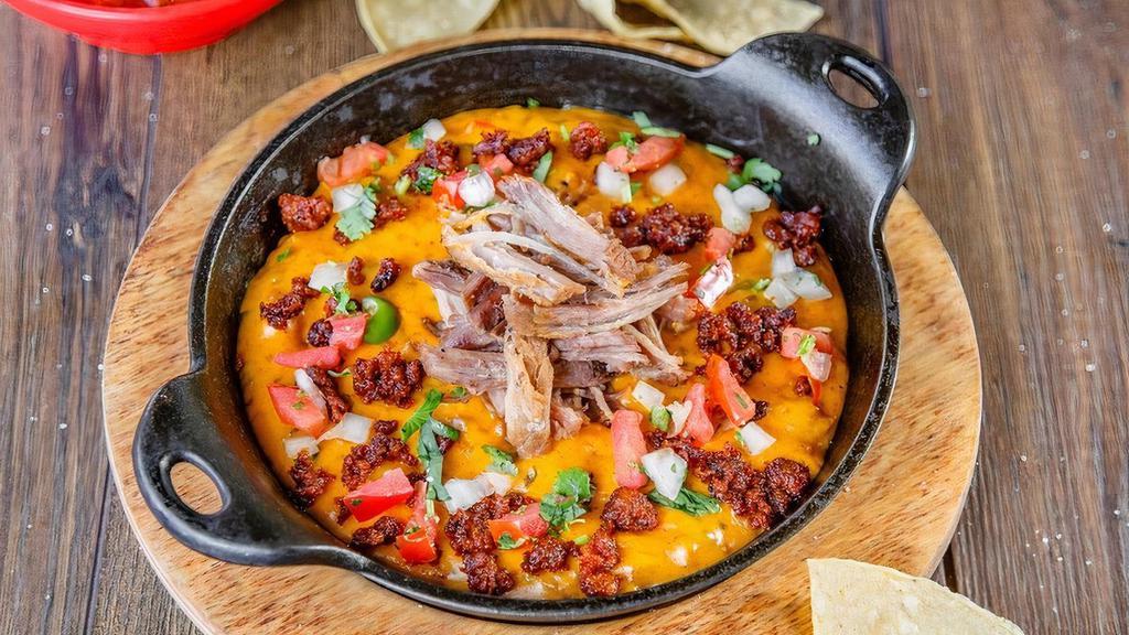 Queso Dip With Carnitas · Two cheese blend, pico de gallo, roasted pasilla peppers, cilantro and carnitas.  Served with warm tortilla chips.