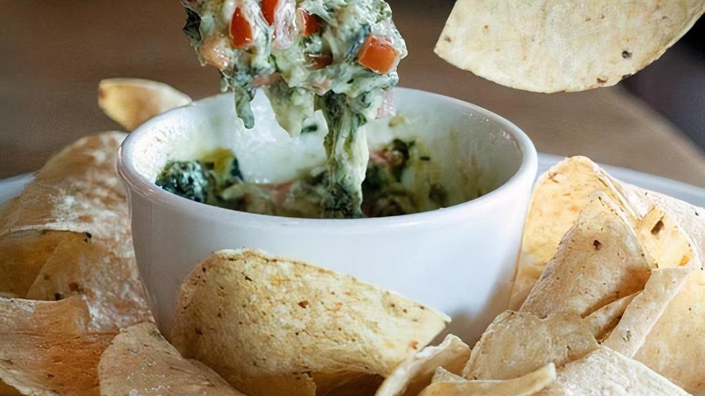 Spinach Artichoke Dip · A creamy blend of spinach, artichoke hearts, melted Parmesan and Provolone cheese. Served with warm pita and tortilla chips. Vegetarian