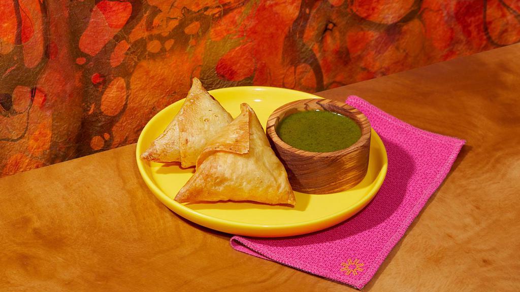 Vegetable Samosas · Two samosas filled with seasoned potatoes and peas and wrapped in a light pastry.