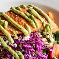 Blackened Salmon W/ Avocado Crema · Blackened salmon served over a bed of quinoa and cabbage cilantro slaw and topped with crumb...