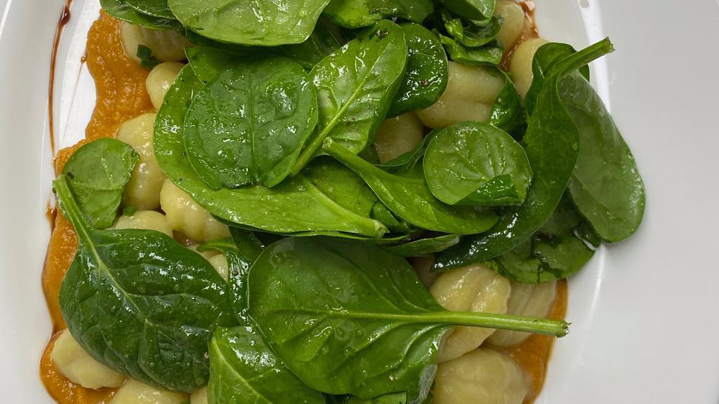 Spinach Gnocchi · Sage buttered gnocchi over a creamy butternut squash purée topped with fresh spinach and greens.