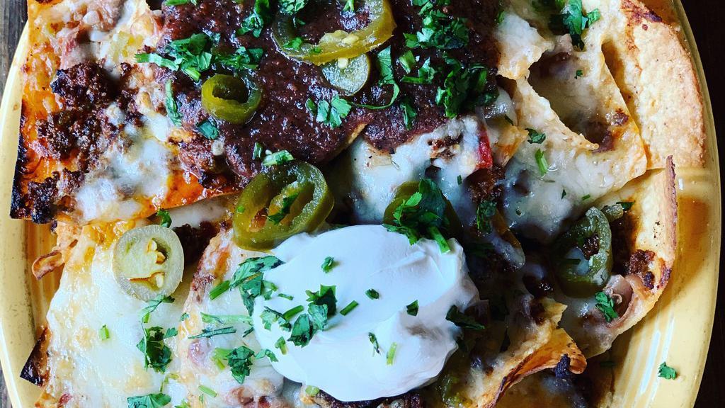 Bolos Nachos · Corn tortilla chips smothered with homemade chorizo, chile verde, bolo beans, jalapeños and cheese, topped with salsa del fuego and sour cream.