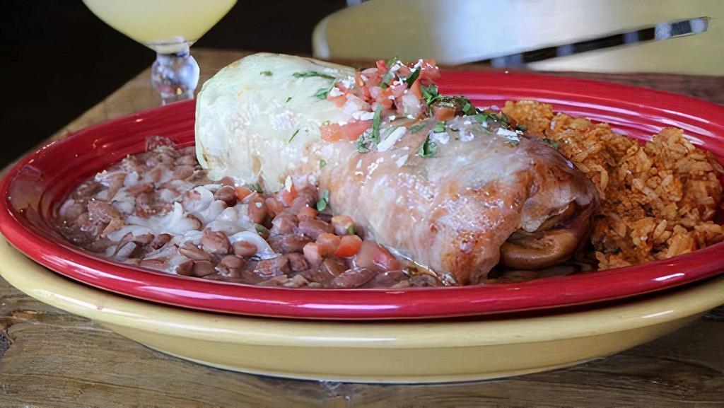 Chimichanga · Flour tortilla + choice of meat + navajo rice + smothered in tomatillo cream sauce + red chile sauce + jack cheese + pico de gallo + served w/ side of navajo rice & bolos (pinto) beans