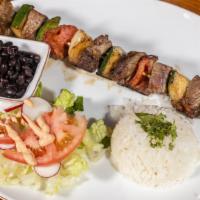 Pincho De Ny · Steak kabob with tomatoes, onions, and peppers. Served with rice beans and salad.