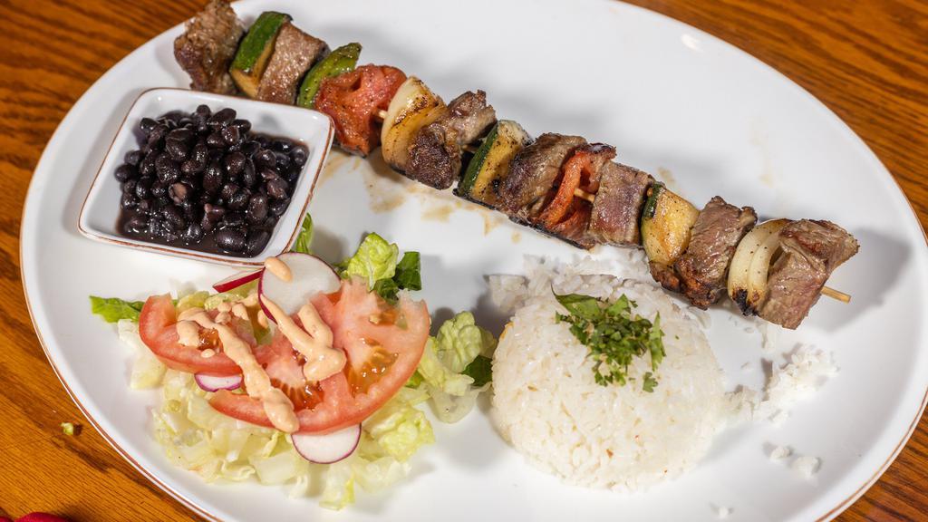 Pincho De Ny · Steak kabob with tomatoes, onions, and peppers. Served with rice beans and salad.