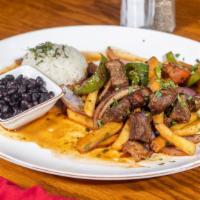Lomo Saltado · Meat strips sautéed with onions, tomatoes, and French fries. Served with rice and beans.