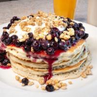 Blueberry Crunch Pancakes · Four buttermilk pancakes loaded with blueberries and topped with yogurt and crunchy granola.