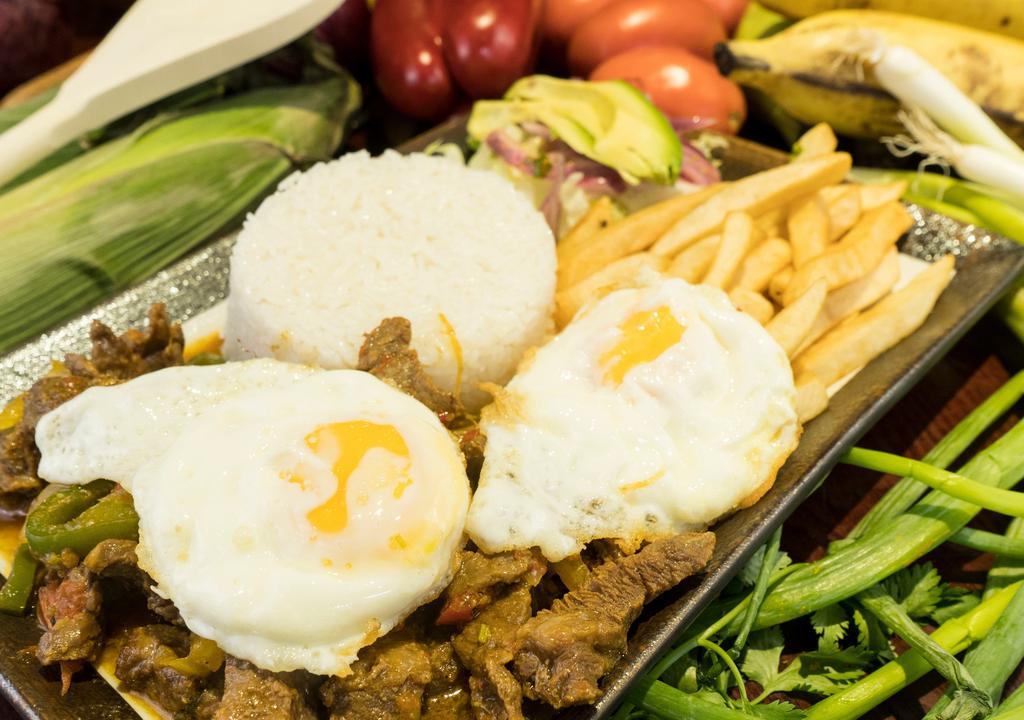 Churrasco Tipo Bistec, Arroz, Huevo Frito, Papas Fritas Y Ensalada · Steak in onions, sauce, rice, fried eggs, French fries and salad, Ecuadorian style.