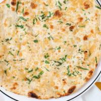 Garlic Naan · Flat, leavened white bread baked in our clay oven, topped with garlic and fresh herbs.