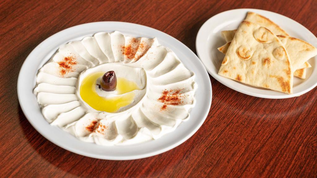 Labneh · Thick and sour yogurt cheese dip garnished with olive oil, paprika and black olives. Served with pita bread.