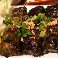 Bo La Nho · Marinated tender beef
wrapped in grape leaves
then grilled to perfection,
topped with peanut...
