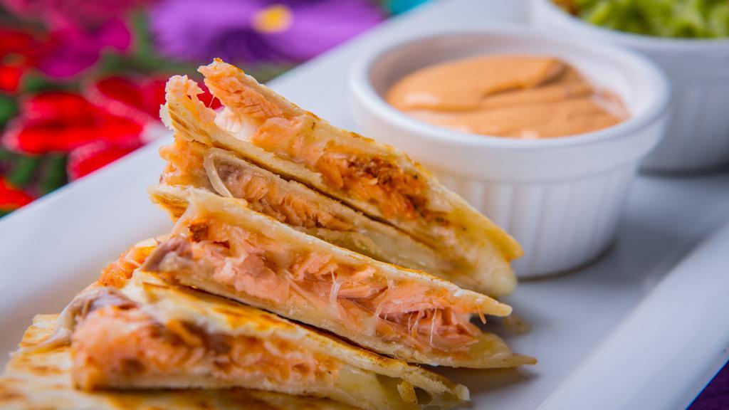 Chilpotle Smoked Salmon Quesadillas · House-made flour tortillas filled with chilpotle smoked salmon, melted cotija and Chihuahua cheeses served with fresh guacamole and creamy chilpotle sauce.