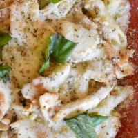 Baked Chicken Pesto · Sliced chicken breast and penne pasta tossed in our creamy pesto alfredo sauce topped with m...