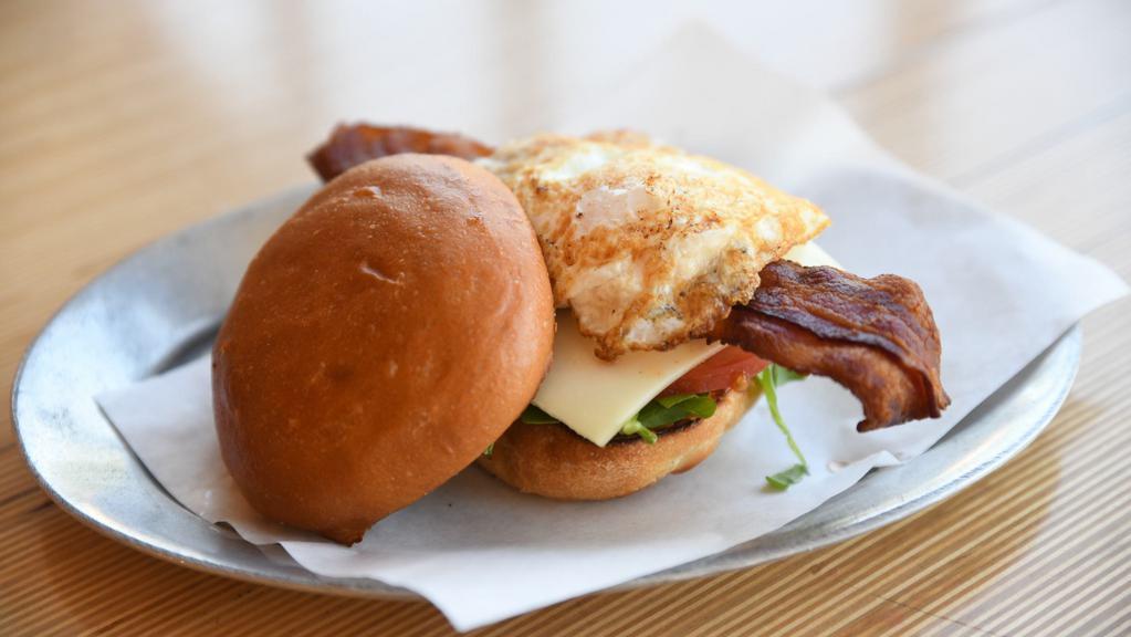 Fried Egg Blt · Fried local/free range egg, applewood smoked bacon, baby arugula, sliced tomatoes, and sharp white cheddar cheese on a toasted egg bun with Unspread