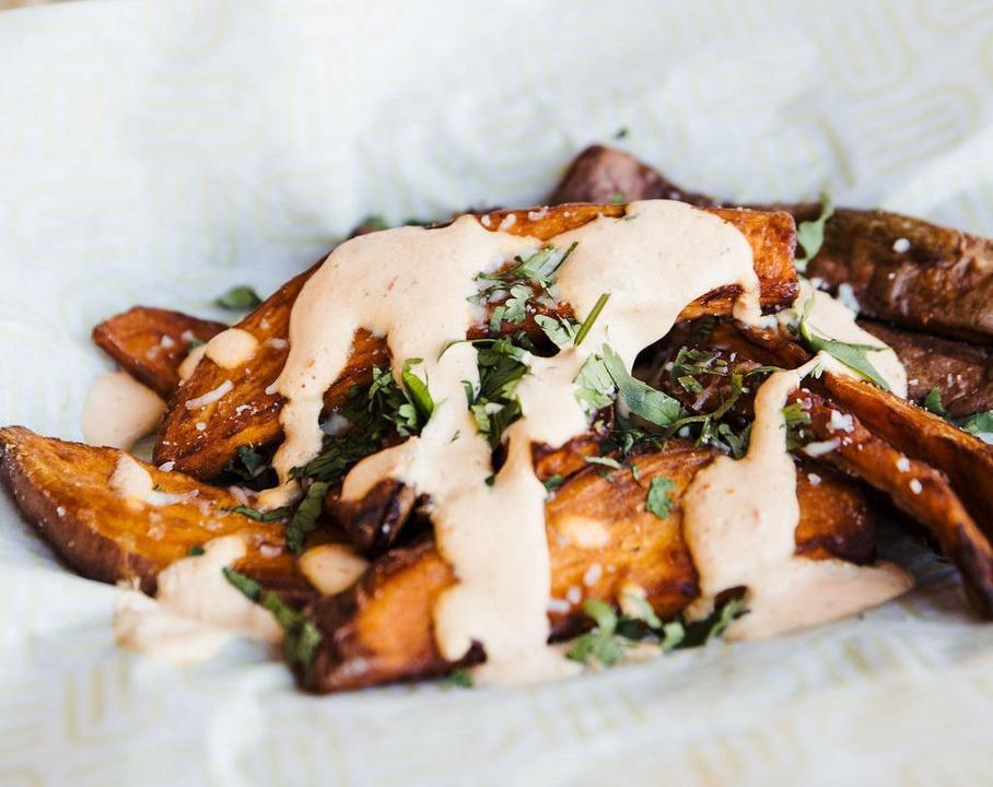 Not So Sweet Potato Wedges · Sweet potato wedges, roasted and fried to perfection, topped with harrisa sour cream, queso fresco and cilantro.