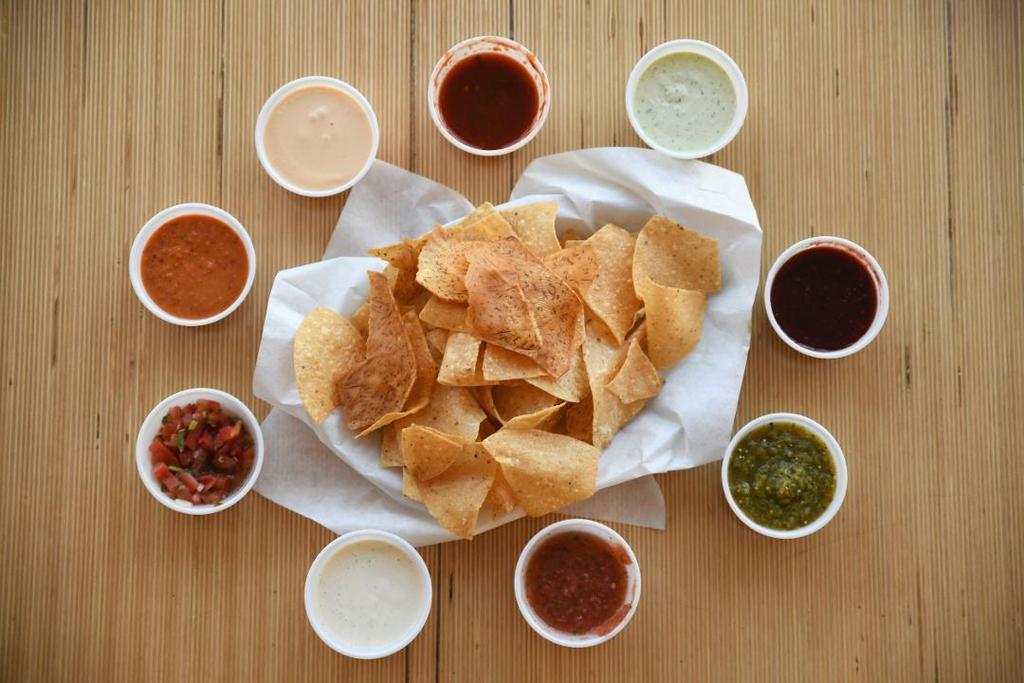 Chips & Flavor · Our blend of thin-cut white corn tortillas, fresh taro chips with your choice of 2 flavors. Choose from seasonal tomato pico, OP sauce, salsa verde, raspberry ancho, habanero ranch, UNcool and fire roasted salsa.