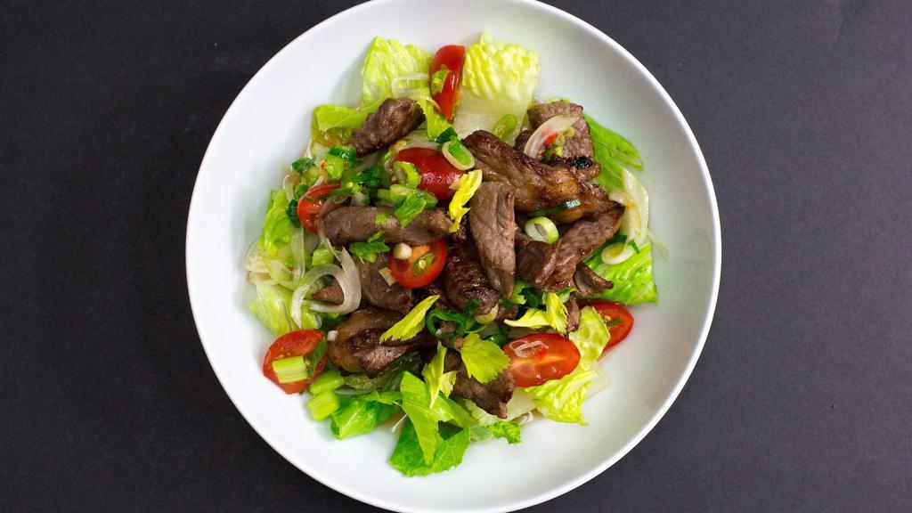 Yum Nua · Mild spicy. Gluten-free. Tenderly grilled Angus NY strip steak sliced into bite-size pieces mixed with spicy sweet-lime juice, garlic, chilies, celery, scallions, tomatoes, onions, and romaine.