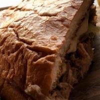 El Cubano · Pressed telera bread filled with pork carnitas, ham, Swiss cheese, pickles & mustard.