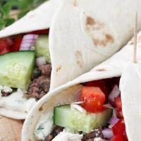 Lamb Gyro · Lamb gyro meat with tomato, cucumber and peppers drizzled with white sauce.