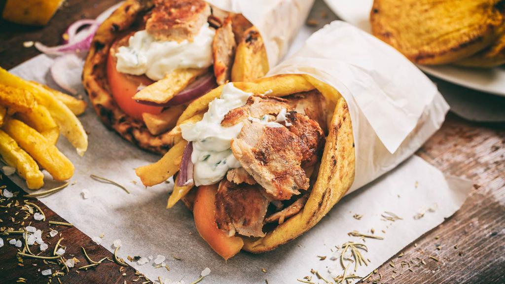 Pork Souvlaki Sandwich · Chunks of seasoned grilled pork wrapped in a pita with lettuce, tomatoes, and onions. Served with a side of tzatziki.